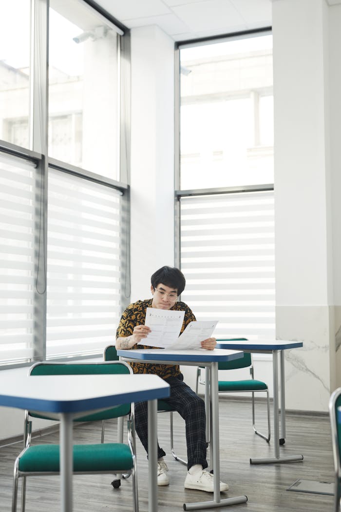 An adult student concentrating on a test in a well-lit classroom environment.