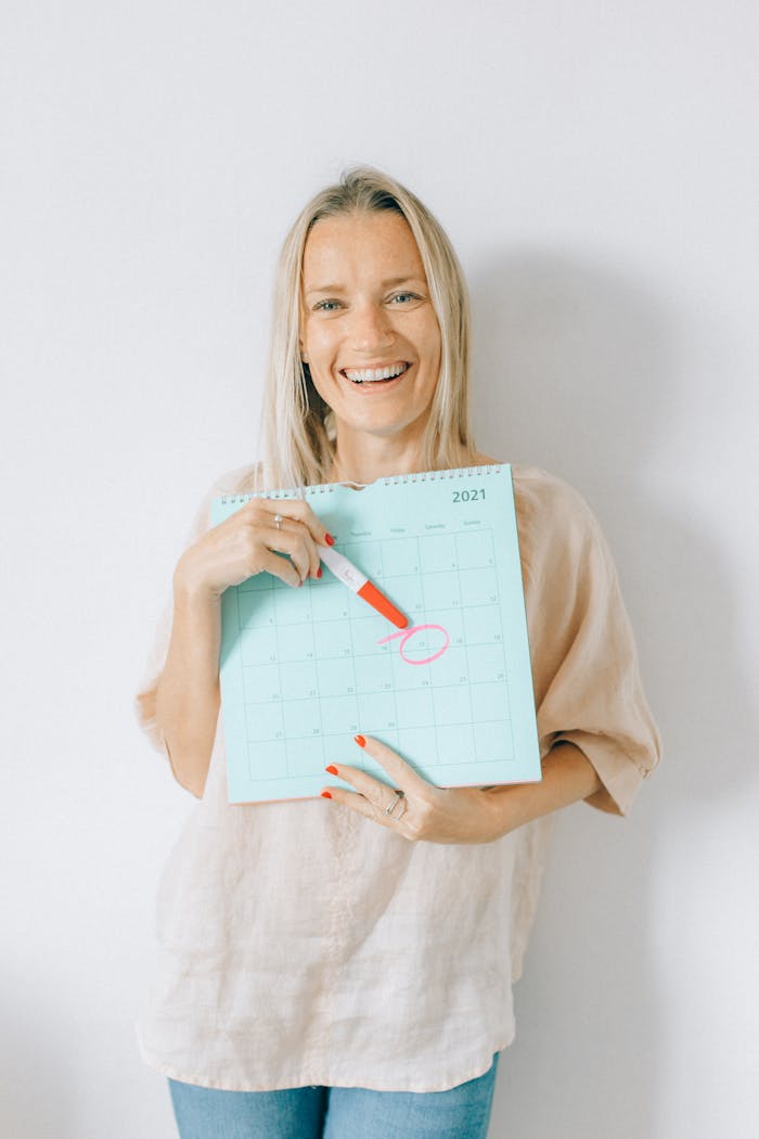 Smiling woman holds calendar marking a date with joy and anticipation.